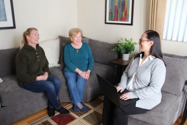 A family with an older adult loved one sitting down and talking to a NaviGuide service coordinator