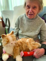 A resident with an animatronic robotic cat on her lap