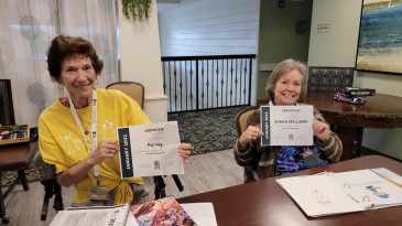 A couple residents smiling and showing off their certificates of completion