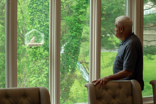 Resident looking through a window at a bird feeder