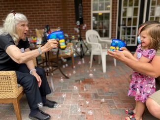 A resident and grandkid blowing bubbles together