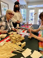 A resident leading a camper in the arts and crafts activity