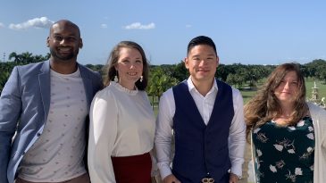 Panelists pose for a photo outside