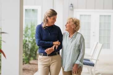 A caregiver and resident walk arm in arm