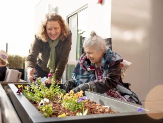 A resident and staff member standing next to a garden bed