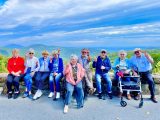 A group of residents posing for a photo in front of a natural landscape