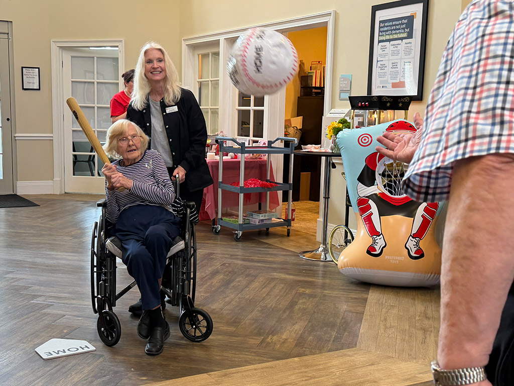 Carol Korte, Liberty Place resident, takes her turn at the bat with Jen Phillips, life engagement assistant.